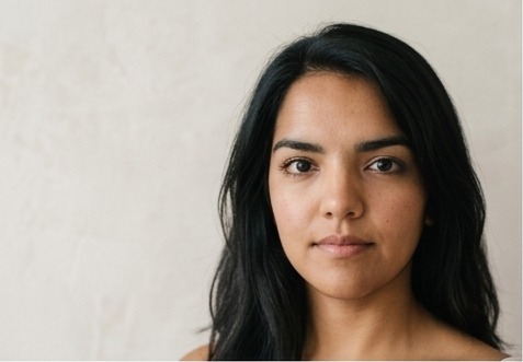 A woman in her thirties with dark hair, direct gaze, real skin texture