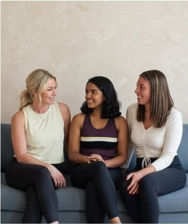 Three women in their thirties talking together on a sofa