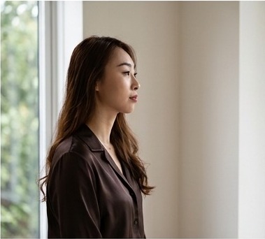 An East Asian woman in her thirties in profile by a window